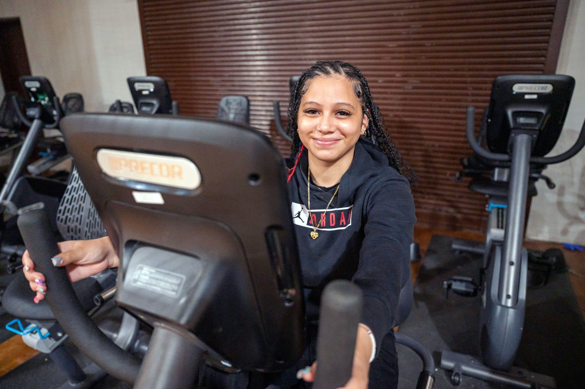 Smiling student on an exercise bike in the school fitness room.